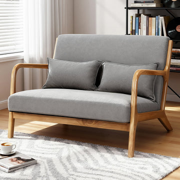 Grey fabric 2-seater sofa with natural wood open-arm frame and two lumbar cushions in living room setting