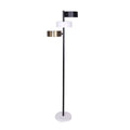 Three-arm floor lamp with black, white, and brass drum shades on black pole with white round base, white background