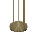 Close-up of brushed gold round base of three-arm floor lamp with three brass poles rising from it on white background