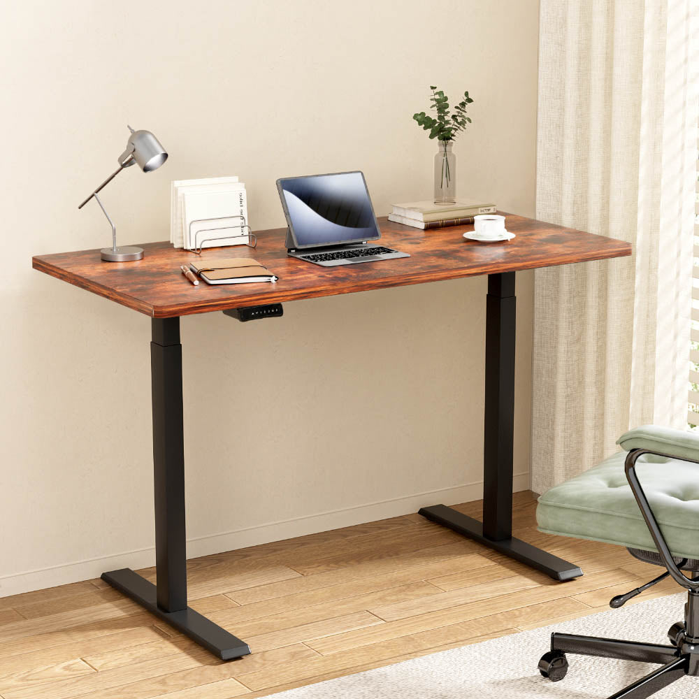 Wooden desk with laptop, lamp, and office items in a home office setting.