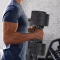 Man in blue shirt holding 45kg Powertrain EON dumbbell, side profile indoor gym brick wall setting