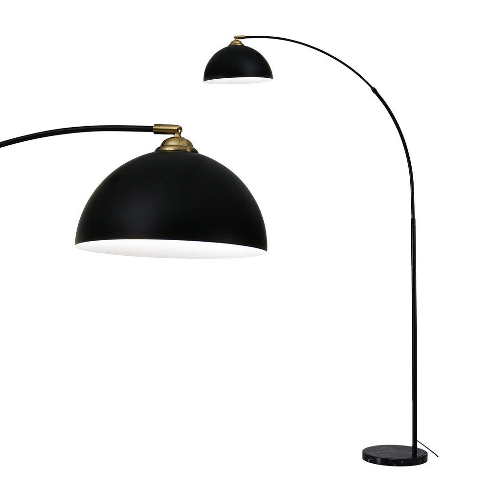 Black arc floor lamp with matte dome shade, brass joint fitting, and round marble base on white background