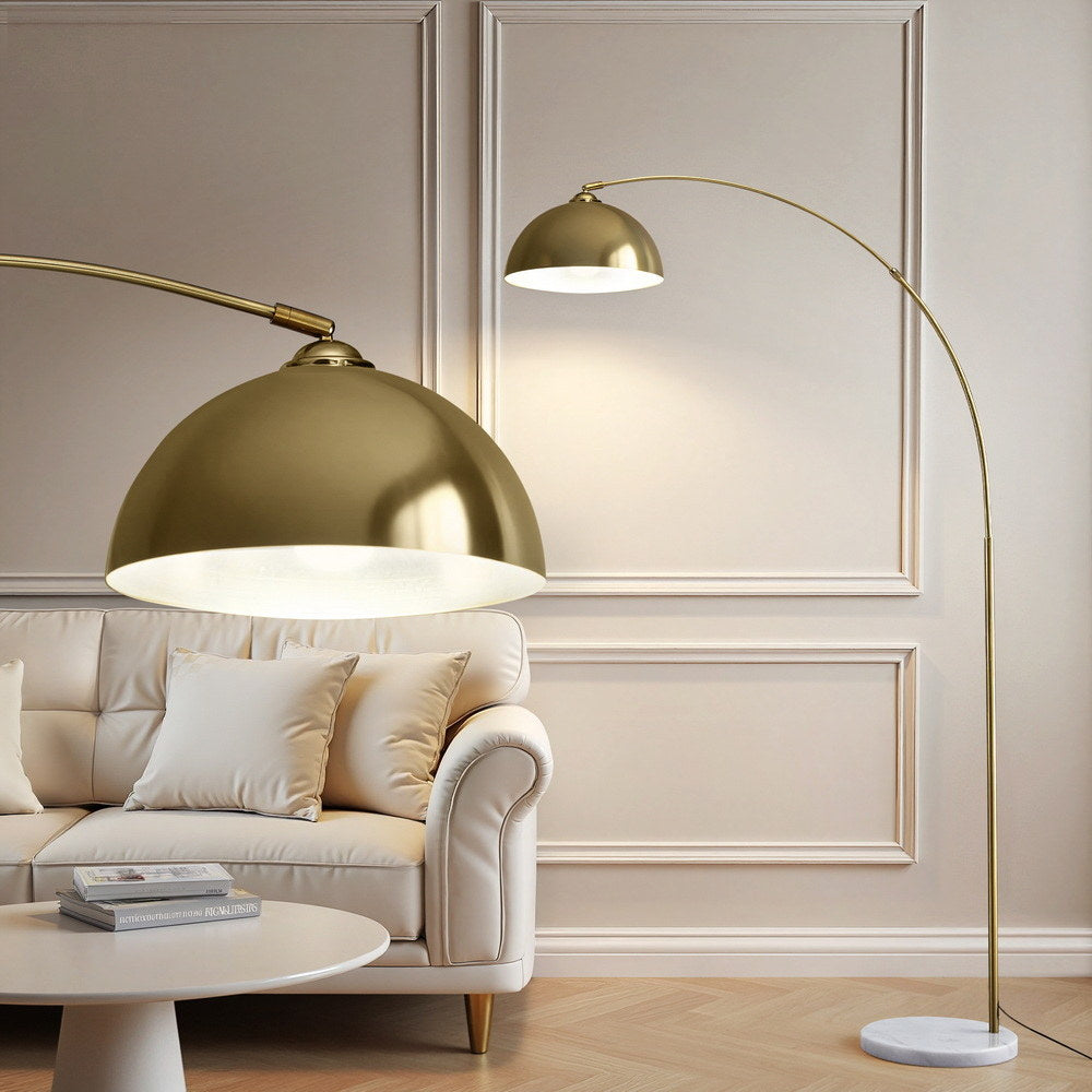 Gold arc floor lamp arching over a cream sofa in a paneled room, with dome shade interior close-up in foreground