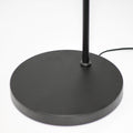 Close-up of flat round black metal base of arc reading lamp with thin pole and black power cord on white background