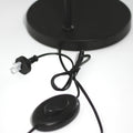 Close-up of arc reading lamp base showing black cord, Australian power plug and oval foot switch on white background