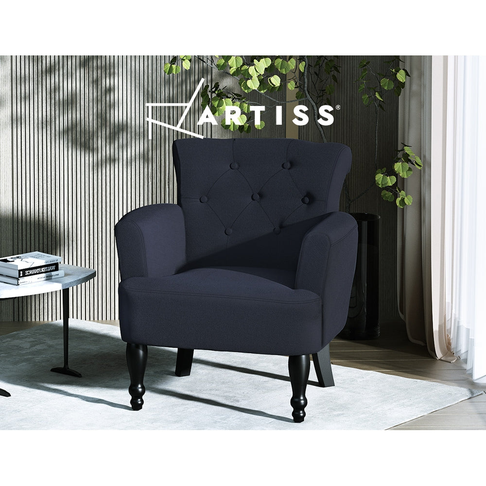 Artiss black linen button-tufted armchair with turned wooden legs in dark styled room with plant, marble side table, and rug