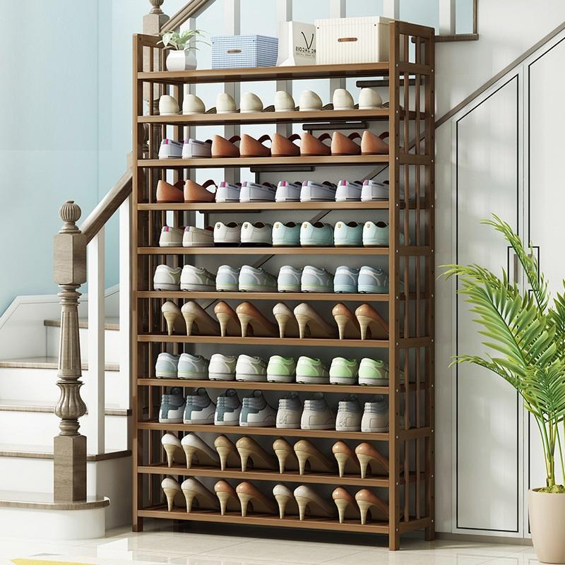 Bamboo 10-tier shoe rack loaded with shoes at base of staircase with palm plant beside it