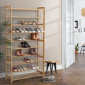 Natural bamboo 9-tier shoe rack loaded with shoes in hallway with French doors plant and small stool