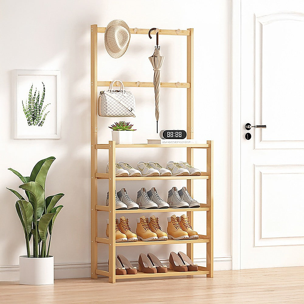 Bamboo hall stand in entryway with hat, umbrella and bag on hooks and four tiers of shoes loaded