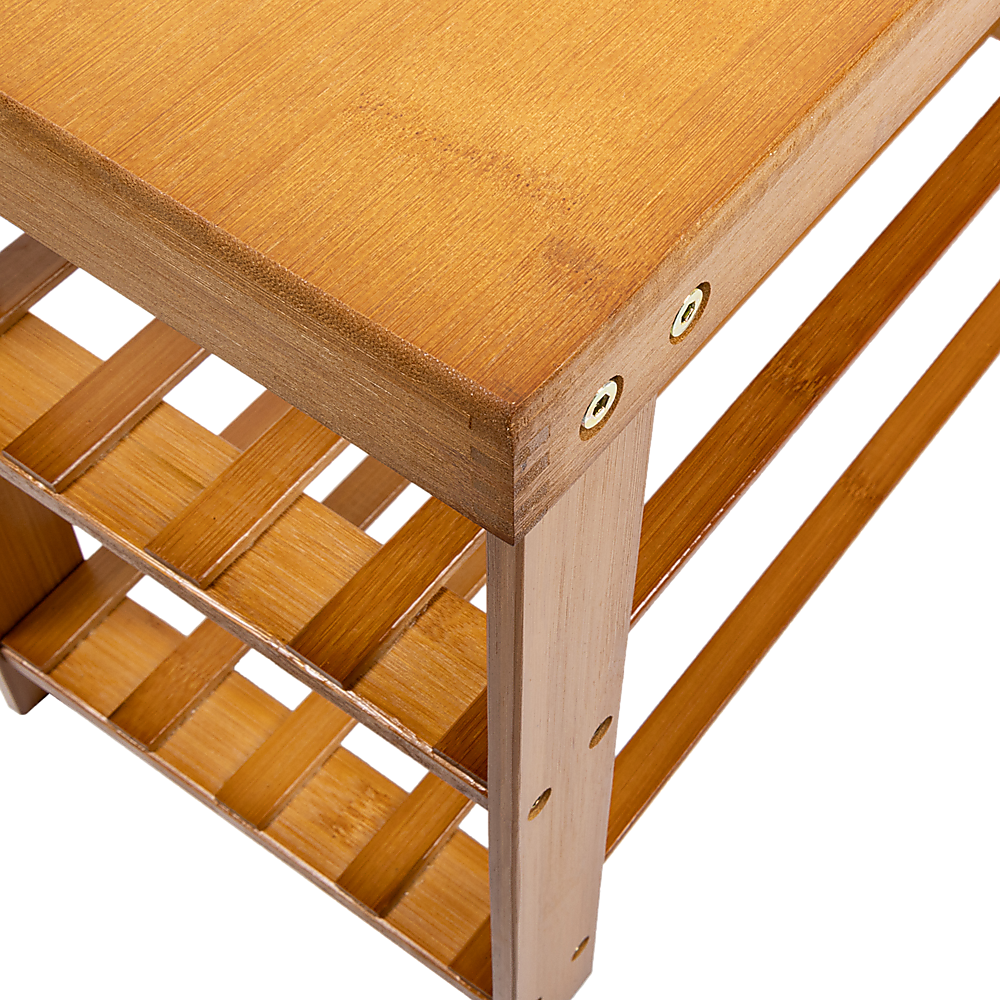 Close-up of bamboo shoe bench corner joint showing brass screws and black anti-slip rubber foot