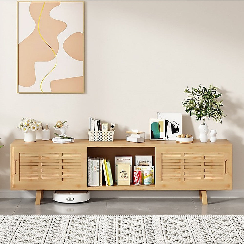 Natural bamboo TV unit lifestyle with center bay open books flowers and plant on top and robot vacuum underneath