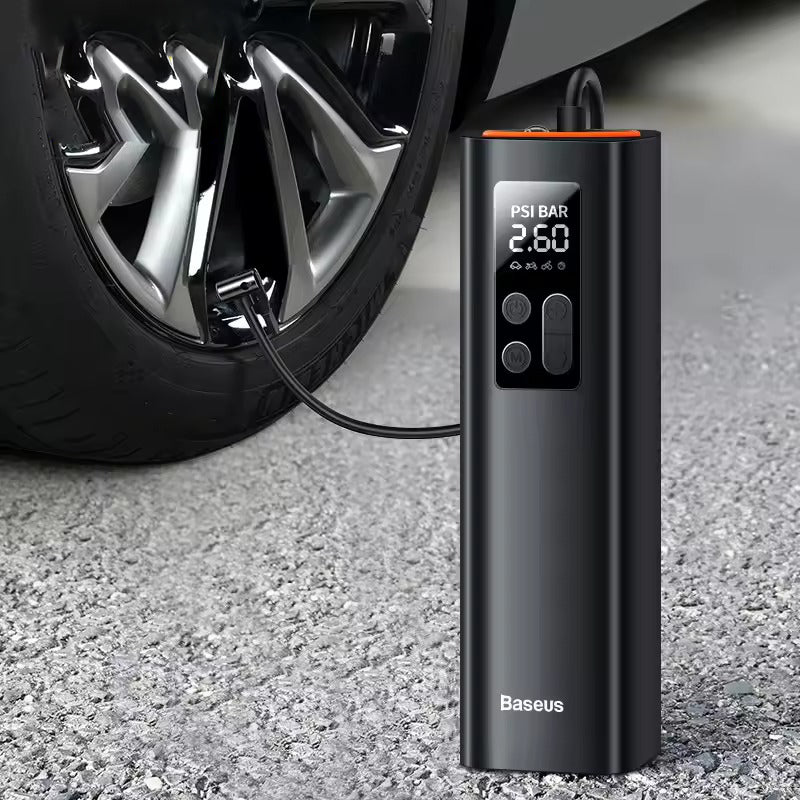 Baseus portable tyre inflator connected to car tyre on asphalt, LCD display showing PSI BAR 2.60, orange cap, control buttons