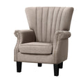 Beige fabric channel-stitched wingback armchair with nailhead trim on arms, angle view on white background