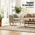 Beige fabric tub armchair in sunny living room with sofa and plants showing Seated in comfort text overlay