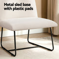 Beige linen accent chair seat close-up with black metal sled base and plastic floor pads, in room with rug and curtains