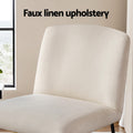 Close-up of beige faux linen accent chair back and seat in room with window, 