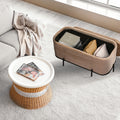 Beige velvet storage bench with black metal base shown open revealing interior compartments with cushions and a book in a