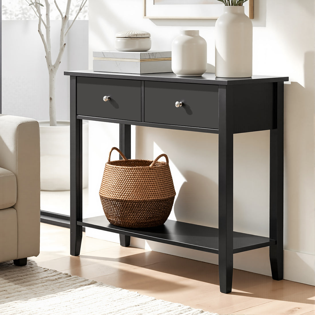 Black console table with two drawers and lower shelf in living room, styled with white vases and wicker basket