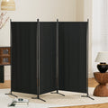 Black 3-panel fabric room divider zigzag configuration in living room lifestyle with blossoming branch lamp and open book