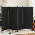 Black 4-panel fabric room divider with X-base pole stands in living room lifestyle with red berry vase lamp and open books