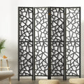 Black 4-panel criss-cross geometric cutout room divider in lifestyle room with fern plant and floor cushions