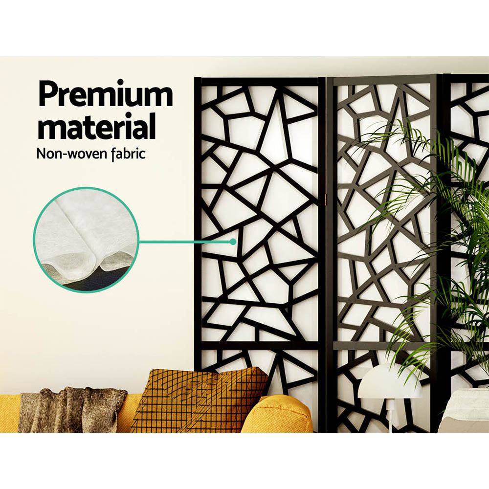 Black 4-panel criss-cross geometric room divider non-woven fabric close-up in lifestyle room with palm plant and sofa