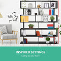 Black S-shaped bookcase in living room with dimensions overlay: 192cm tall, 80cm wide, holds 3kg per shelf