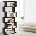 Black 6-tier S-shaped display bookcase loaded with books, vases and baskets in living room with cream sofa