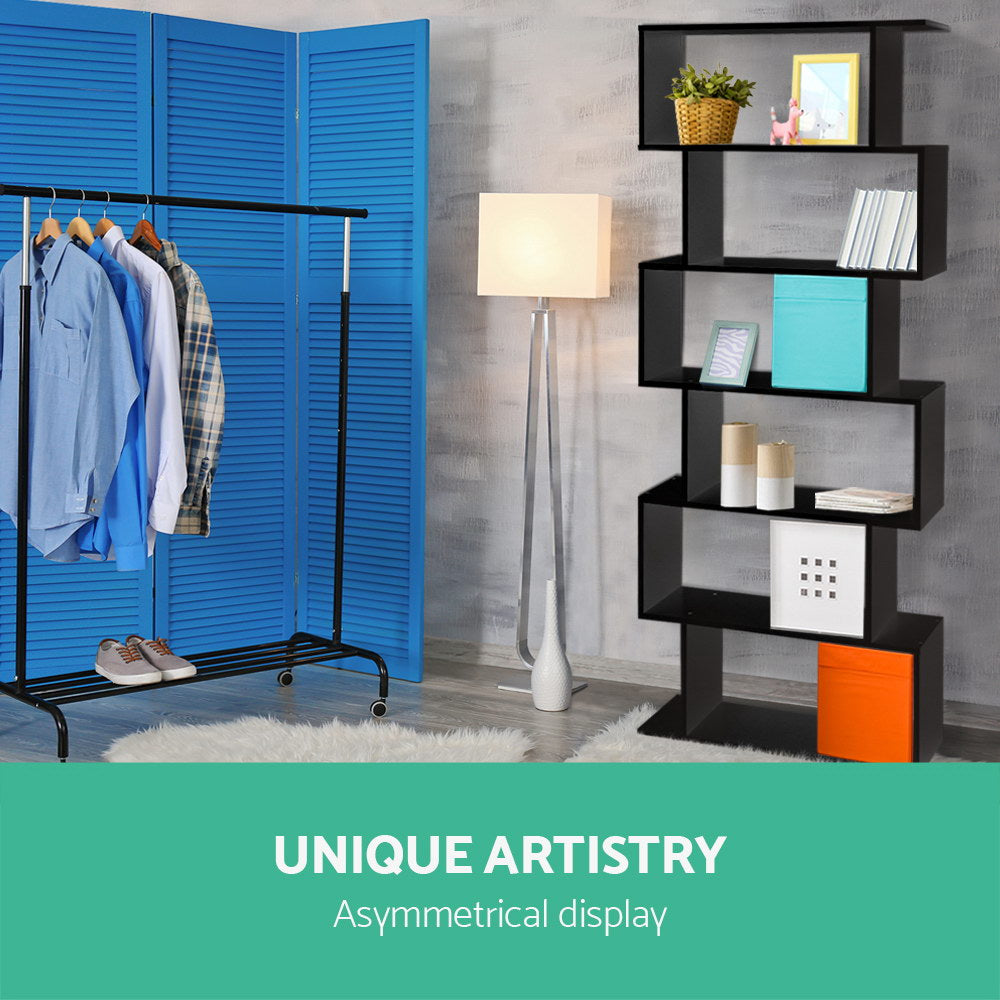 Black S-shaped bookcase in room with blue room divider and clothes rack, text reads Unique Artistry