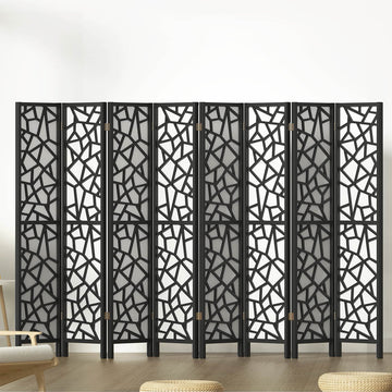 Black 8-panel MDF room divider with geometric star pattern cutouts in lifestyle room with chair and ottomans
