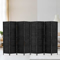 Black 8-panel woven paper rope room divider in lifestyle room against white wall with hanging plant and rattan pendant lamp