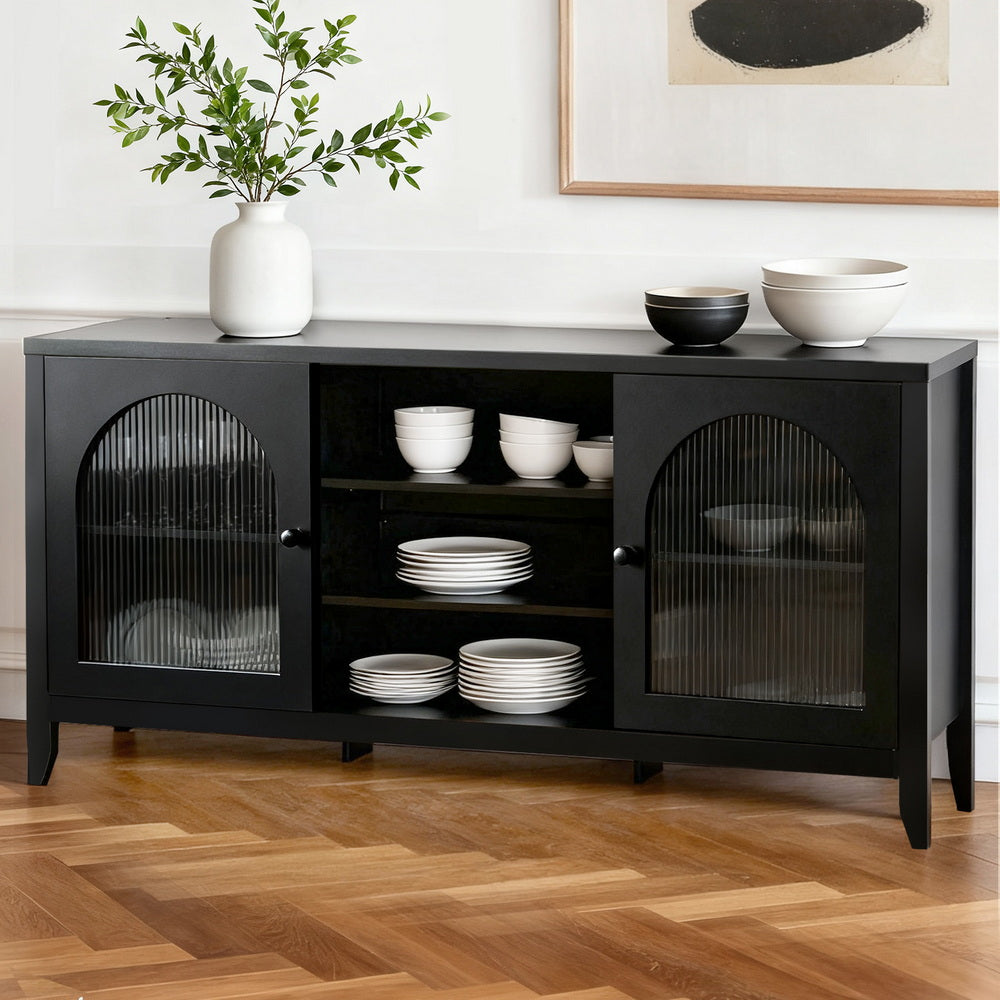 Black arched glass sideboard in dining room with white bowls and plates on open shelves, vase with greenery on top