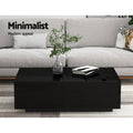 Black high-gloss coffee table with open storage drawers styled in a living room with grey sofa, plant in glass vase and