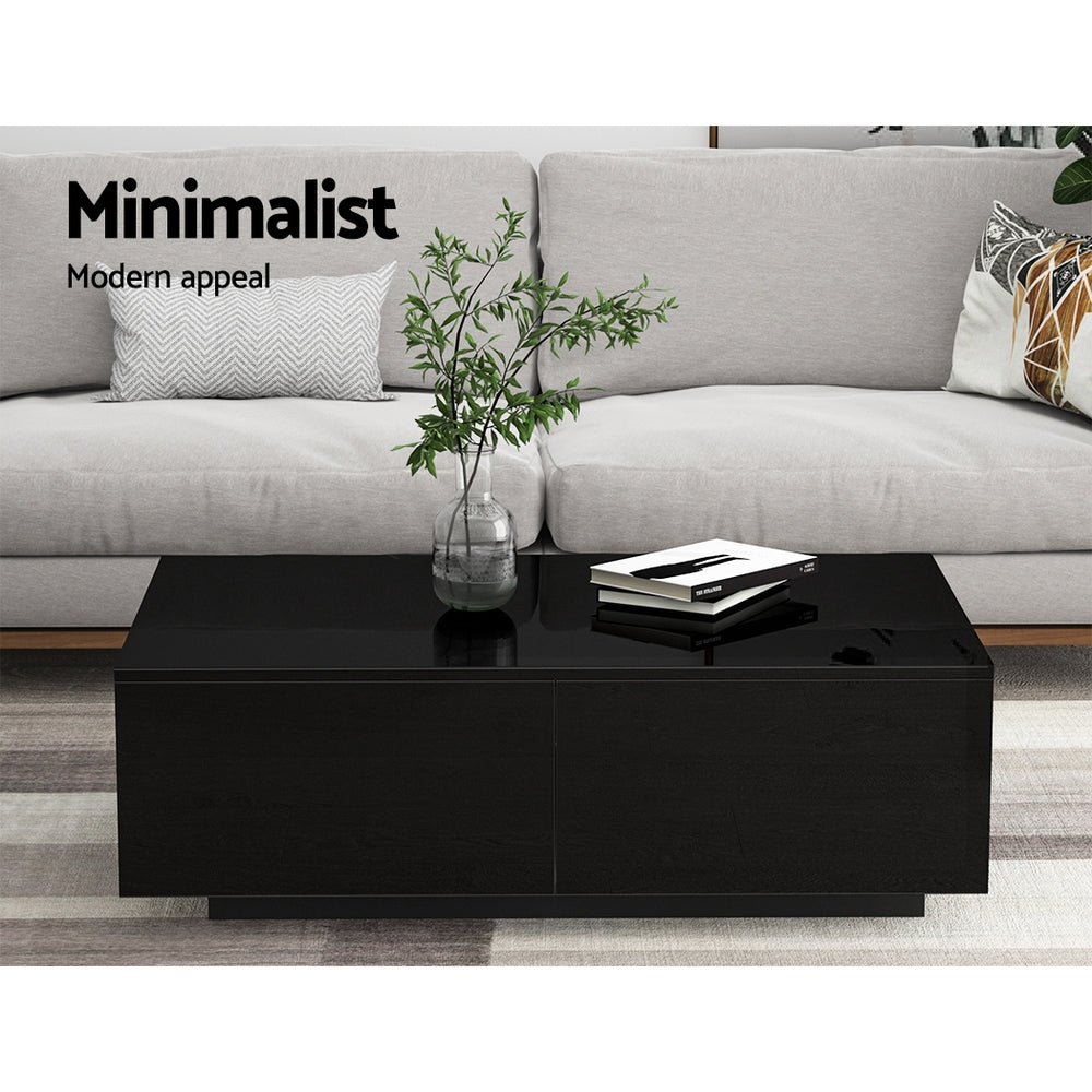 Black high-gloss coffee table with open storage drawers styled in a living room with grey sofa, plant in glass vase and