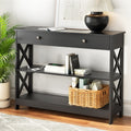 Black console table with one drawer, X-cross side panels, three tiers, built-in power outlet on middle shelf, lifestyle shot