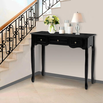 Black wooden console table with three drawers and ornate cabriole legs styled with flowers and lamp by staircase