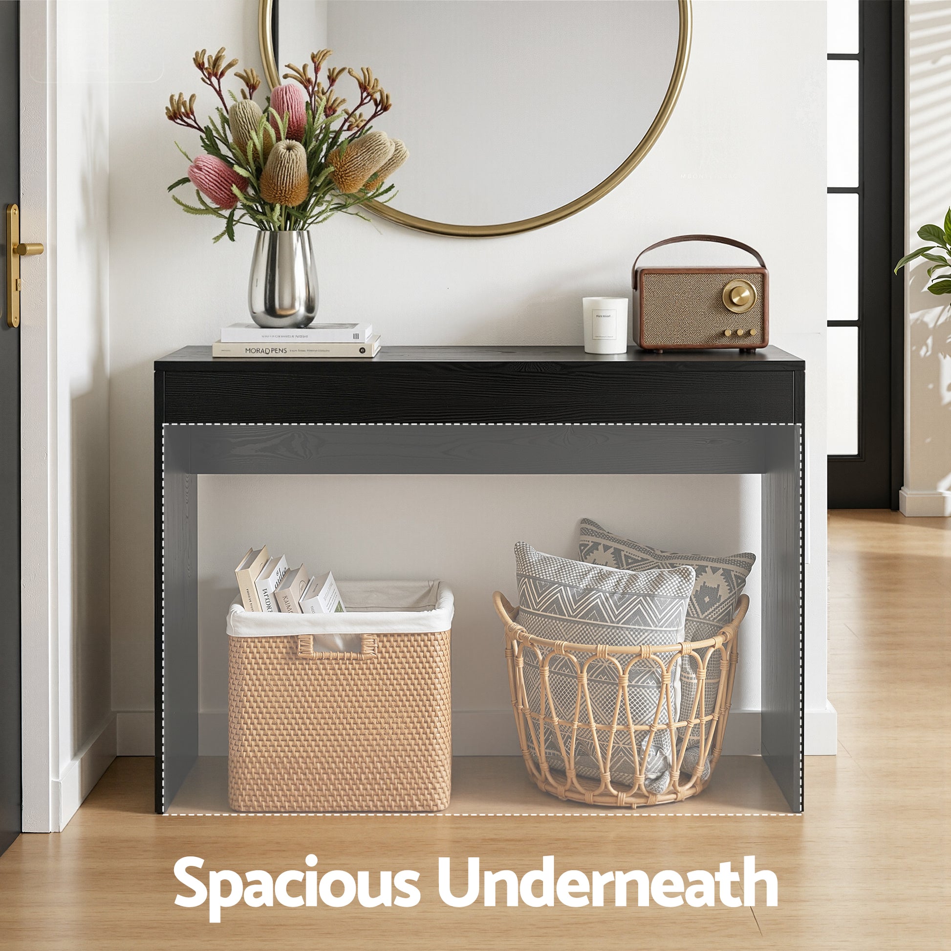 Black console table in entryway with "Spacious Underneath" callout, open base holding rattan baskets with books and cushions