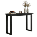Black console table with U-sled frame legs styled with bowl, dried flower vases and small decorative bottles, angle view