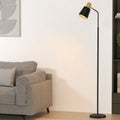 Black and gold reading floor lamp lit beside grey sofa in lounge room with abstract art print and bookshelf in background
