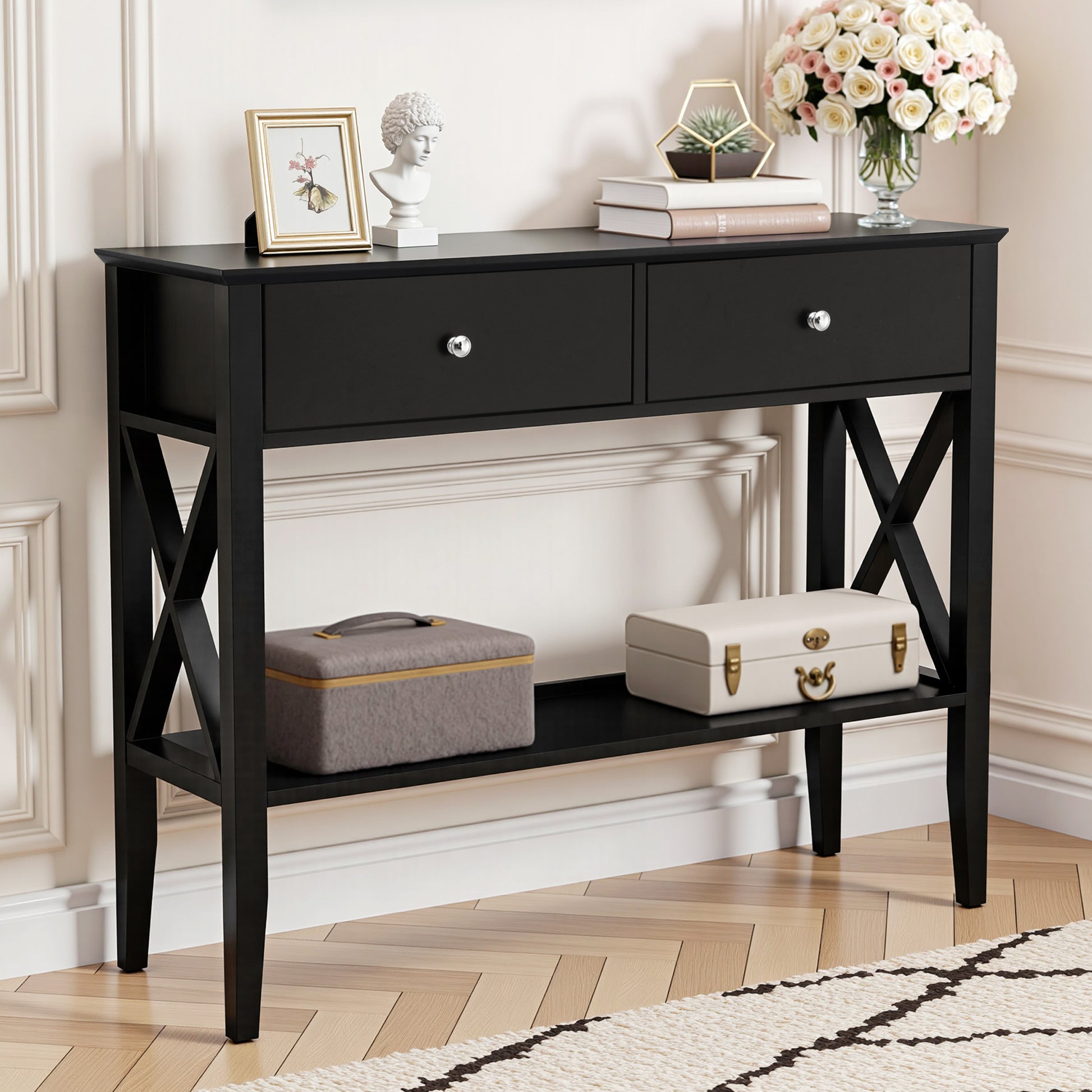 Black hall table with two drawers, chrome knobs, X-cross side panels, lower shelf, styled with decor in classic room setting