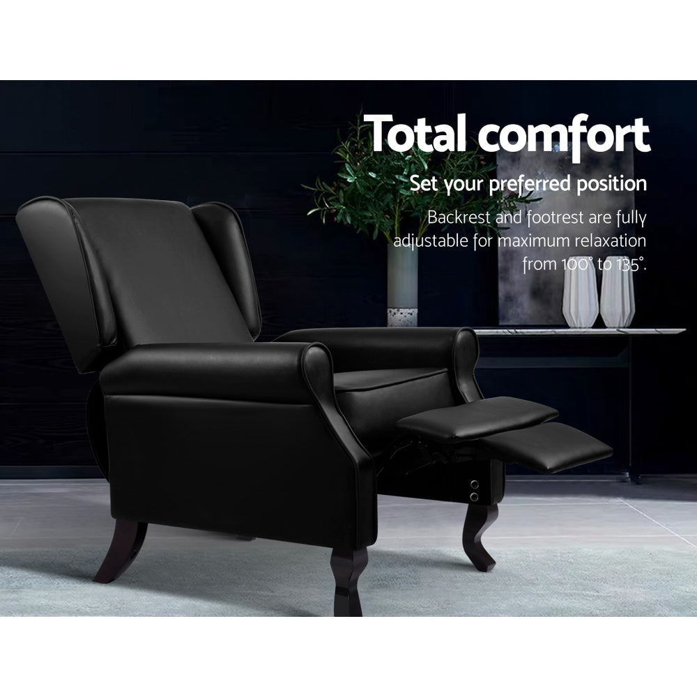 Black faux leather wingback recliner with footrest extended in dark scene, reclines 100 to 135 degrees, Total comfort text