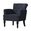 Dark charcoal linen armchair with button-tufted back, rolled top, curved armrests, and turned black wooden legs, angle view
