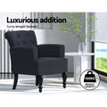 Black linen button-tufted armchair in styled room with marble side table and window, 