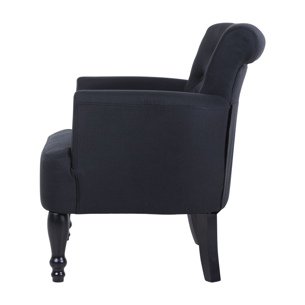 Dark charcoal linen armchair side view showing rolled curved back, button tufting, and turned black wooden legs