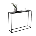Slim black metal console table with grey vase holding flowers and small white figurine on top, white background