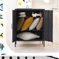 Black metal locker cabinet doors open showing books on top shelf and cushions on lower shelves in lifestyle setting