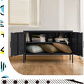 Black two-door metal sideboard cabinet open in room with books and decor on top shelf, cushions below