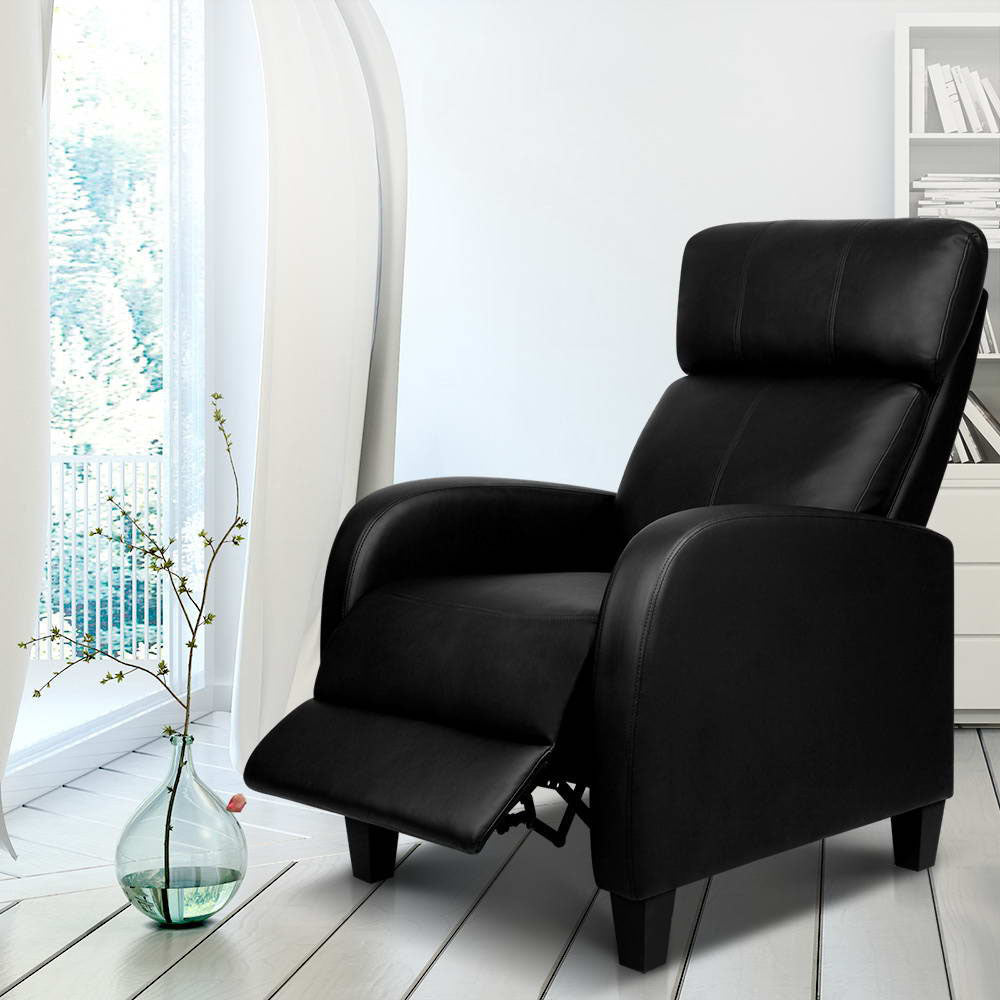Black PU leather recliner chair in reclined position with extended footrest, in white room with arched mirror and bookshelf