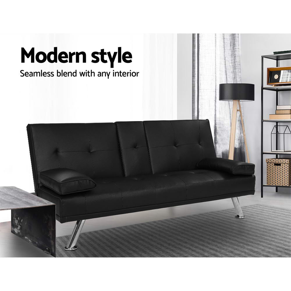 Black PU leather sofa bed in living room with tripod floor lamp, metal shelf and marble coffee table