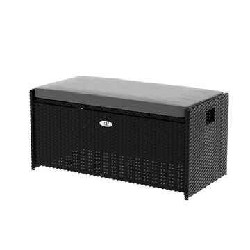 Black rattan outdoor storage bench with grey cushion on top, silver badge on front, three-quarter angle, white background